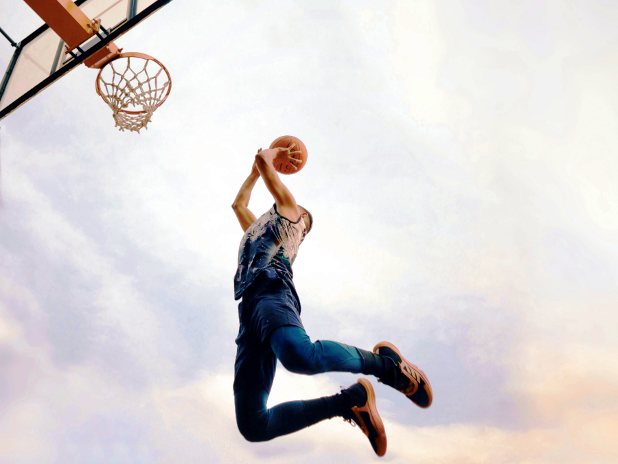 Giocatore di basket durante un salto che evidenzia il carico sul tendine rotuleo durante la prestazione sportiva.